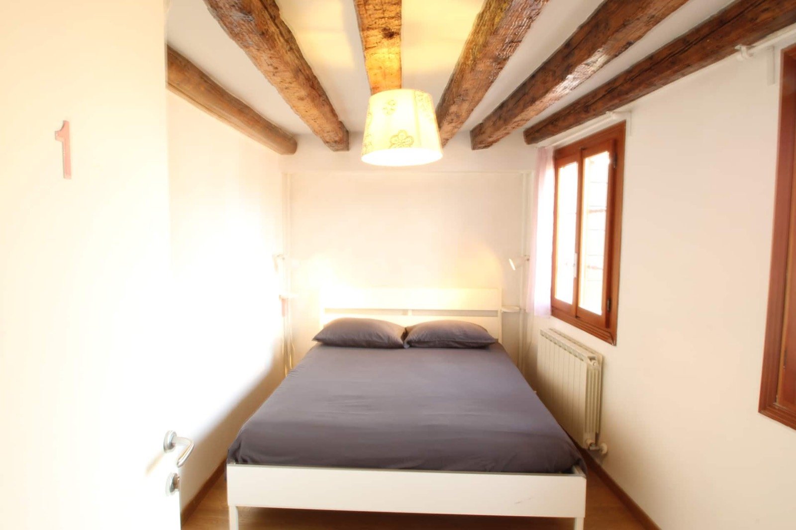 Camera 1 — Letto matrimoniale, travi a vista e finestra